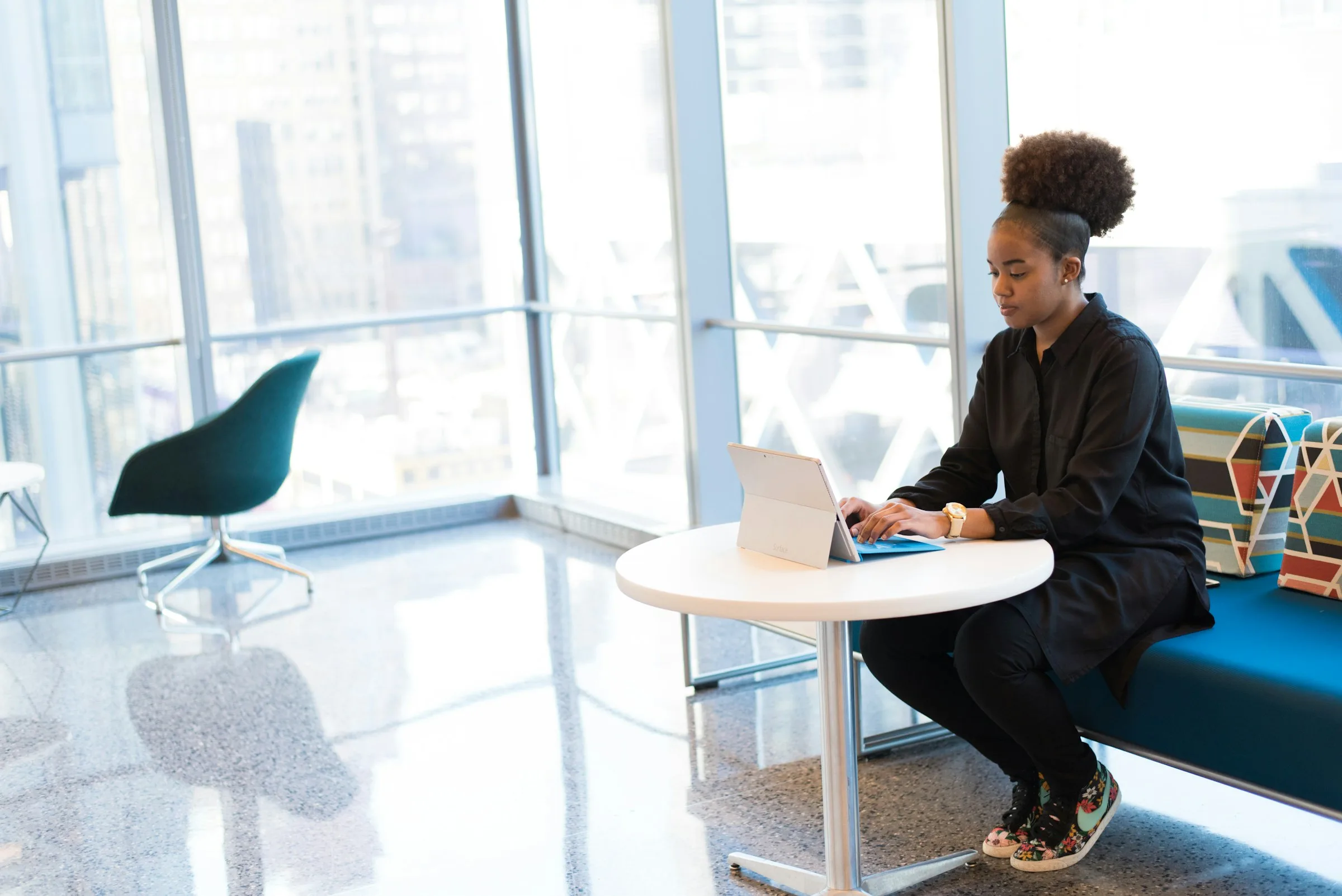 A woman working at a laptop in a glass-walled office